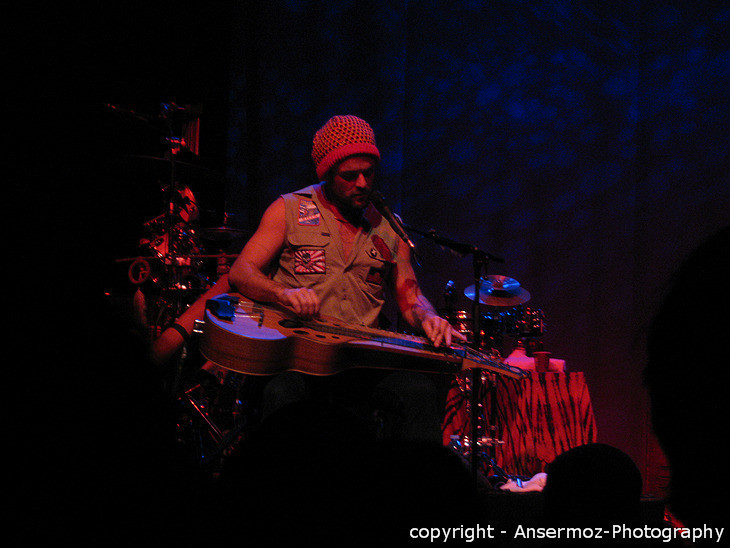 Xavier Rudd playing slide guitar on stage in concert in Montreal